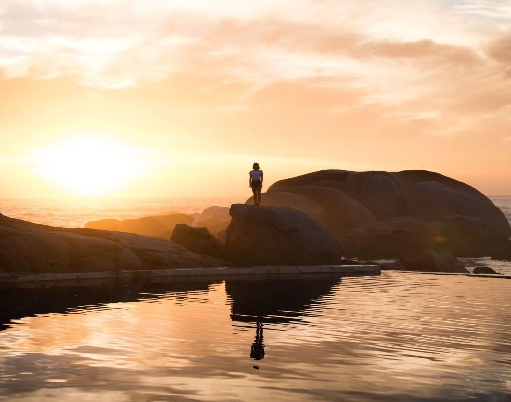 individual standing alone on coastline during sun set